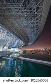 Louvre, Abu Dhabi, United Arab Emirates - Dec.29, 2017: Pools Of The Museum At Night Under The Wing Of Dome With A View Of The City Lights