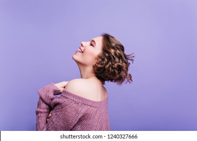 Lovable European Woman With Short Haircut Enjoying Photoshoot In Purple Room. Indoor Portrait Of Enthusiastic Curly Girl In Knitted Outfit Happy Smiling.