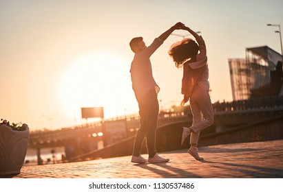 愛在空氣中！可愛的浪漫夫婦花時間在一起在城市。帥氣鬍子的男人和有吸引力的年輕女子都在愛河。在日落時跳舞