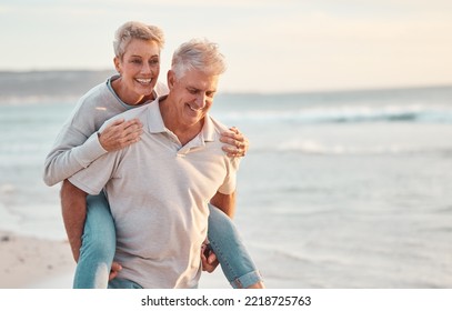 Love, Beach And Piggyback With A Senior Couple Walking By The Sea Or Ocean While On A Date In Summer Together. Nature, Earth And Water With An Elderly Man And Woman Pensioner Taking A Walk On A Coast