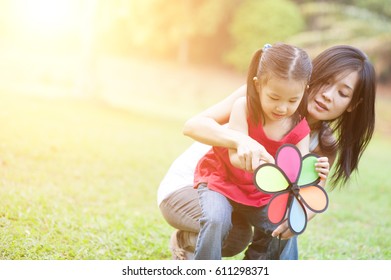 Love Between Mother And Daughter, In The Park. Asian Family Outdoor Fun, Morning With Sun Flare.