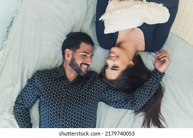 Love between two people. Happy heterosexual married couple lying on bed, looking each other in the eye in a romantic way, and smiling. High quality photo