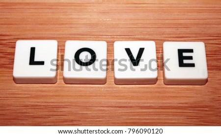 "Love" Board Game Tiles on Wooden Textured Background