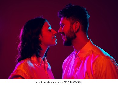 Love, care, support. Closeup young and happy man and woman look at each other isolated on dark trendy color background in neon light. Human emotions, youth, love and lifestyle concept. Beloved people - Powered by Shutterstock