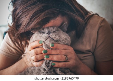 The love of a cat and its owner. Gray Scottish straight cat smiles. Tenderness for a pet. The owner pressed her head against the muzzle of the cat. - Shutterstock ID 2196963479