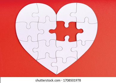 Love, charity, donation, helping concept. Missing piece of jigsaw puzzle in heart shape on red. Looking for love partner. Uncompleted puzzle. Relationship. Mental health problems, heartache