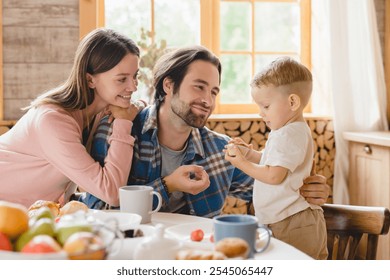 Love and childcare concept. Baby adoption and parenthood. Caucasian parents feeding little small kid child infant new born baby at home kitchen. Family moments together. - Powered by Shutterstock