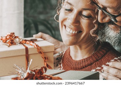 Love and christmas gifts concept leisure activity with young mature man and woman exchanging presents in winter holiday at home with smile and happiness. Couple in relationship hug and enjoy together - Shutterstock ID 2396417667