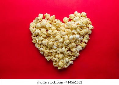 Love Cinema concept of popcorn arranged in a heart shape on red background
