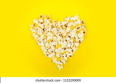 Love cinema concept of popcorn. Heart shaped white fluffy popcorn on yellow retro background