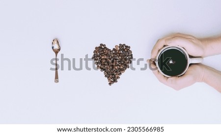 I love coffie a human hand holding a cup of coffie on a whie background with a spoon and coffie beans heart.