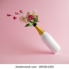 Love concept. Flowers fly from a bottle of champagne on a pink background.