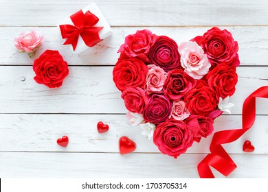 Love concept - heart made of selfmade paper artificial flowers like roses and ranuncules and a wrapped gift against white rustic wooden background. Flatlay - Powered by Shutterstock