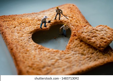 Love Concept. Sad Relationship. Group of Worker Miniature Fixing a Burned Sliced Toasted Bread with a shape of Heart - Powered by Shutterstock