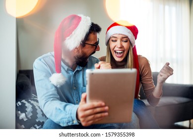 Love couple with Christmas hat on head using tablet and credit card to buying online - Powered by Shutterstock