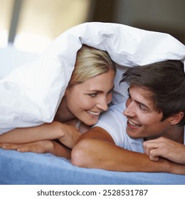 Love, couple and happy with duvet in bed, comfortable and bonding with connection in relationship. Bedroom, man and woman with fabric for relax, trust and commitment with dating in morning at home - Powered by Shutterstock