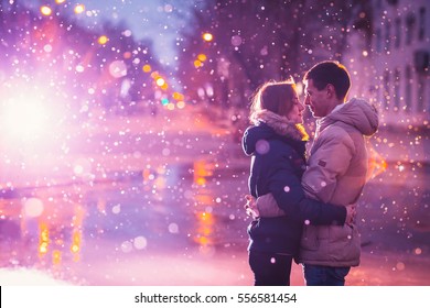 No amor casal beijando na neve na rua da cidade noite. Filtrado com grão e luz piscando