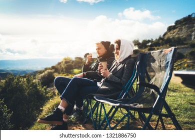 Love Couple Sit In Camping Chairs On Top Of Sun Flare Mountain, Travelers Drink Tea On Cup Enjoy Nature, Romantic Look Into Distance On Background Of Panoramic Landscape, Weekend Concept