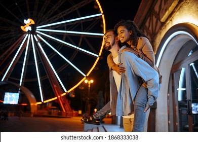 Love couple walking in night amusement park