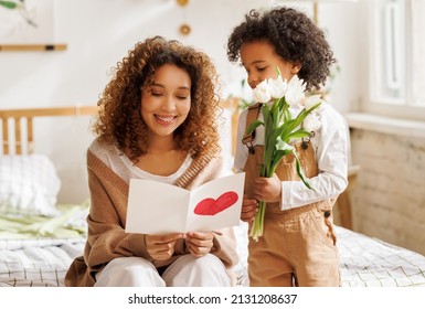 With love  Cute excited little boy son giving his mom flowers   greeting postcard  happy mother thanks  child   at home  Mother's day celebration concept