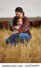 Love, Family And Care With A Mother And Daughter Hugging In A Field Outside On A Farm. Cattle Farmer And Little Girl In The Farming, Agricultural And Dairy Industry On A Meadow Or Pasture Outdoors