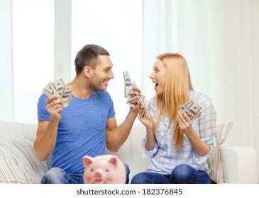 Love, Family, Finance, Money And Happiness Concpet - Smiling Couple With Money And Piggybank Ot Table At Home