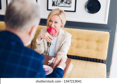 love at first sight. rapeed, speed date. close up photo. gorgeous blond woman smelling the rose which was given by her friend - Powered by Shutterstock