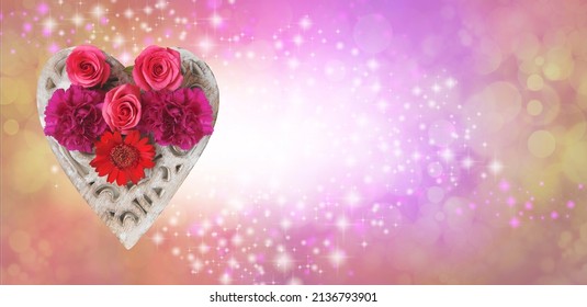 Love And Flowers Message Background - Red Pink Flower Heads Arranged On A Wooden Heart Against A Peachy Pink Gold Bokeh Background With White Centre And Sparkles Providing Space For Message
