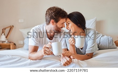 Love, happy and a couple with coffee in bed on beautiful morning at home. Weekend, wake up and smile, woman and man relax with hot drink in bedroom. Romance, happiness and drinking sweet tea together