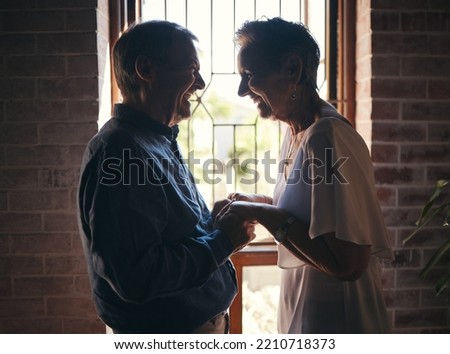Love, happy family and senior couple laugh and relax in dark room, bond and share funny joke in their home. Retirement, humour and affection by sweet elderly man and woman smile, enjoy time together
