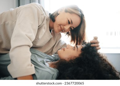 Love, happy and lesbian couple with intimate moment on bed for bonding or relaxing together. Smile, romance and young interracial lgbtq women with affection in the bedroom of modern apartment or home - Powered by Shutterstock