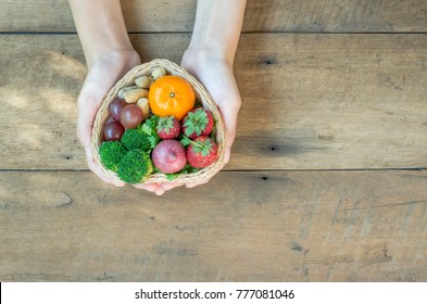 Love healthy food concept. Hands holding vegetables and fruits basket in heart shape on brown wood table