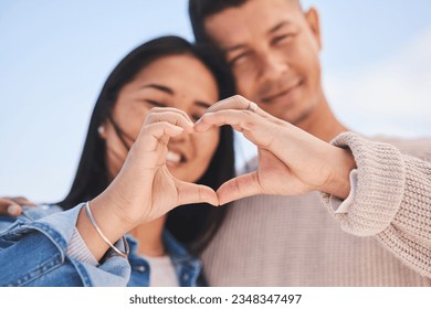 Love, heart hands and portrait of happy couple with blue sky, nature and holiday travel for summer. Care, marriage and smile, loving sign language emoji with man and woman on beach vacation together. - Powered by Shutterstock