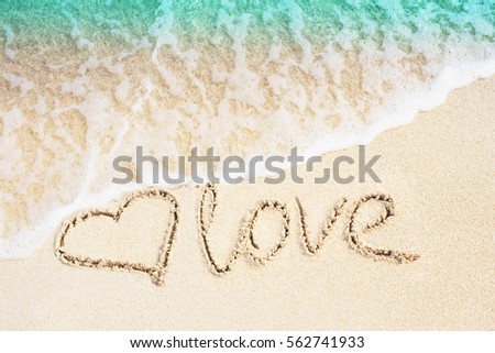 Love and heart symbol handwritten on tropical beach with soft wave on background