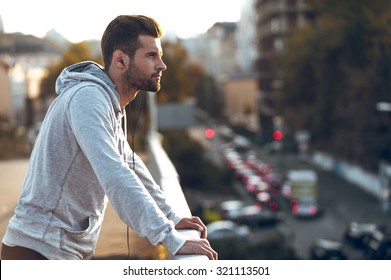 In love with his city. Side view of pensive young man in headphones looking away while standing on the bridge - Powered by Shutterstock