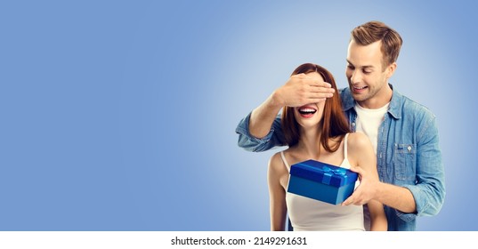 Love, holiday sales, shop, rebates, discounts offers concept - happy amorous couple with blue gift box. Blue color background. Copy space area. Valentines Day. Astonished people. Astonishment.
