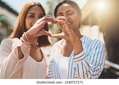 Love Keeps Your Friendships Strong. Shot Of Two Cheerful Young Women Forming A Heart Shape With Their Hands Together While Standing Outside During The Day.