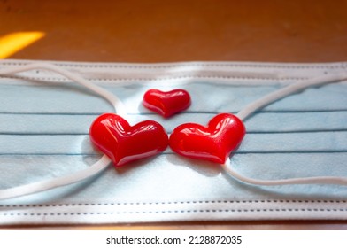 Love And Kinship In Covid 19 Coronavirus Quarantine Pandemic Times.Family Reunion.big And Small Red Hearts Placed On Top Of Medical Safety Sterile Mask.Separated Family.Mother's Day.Epidemic Isolation