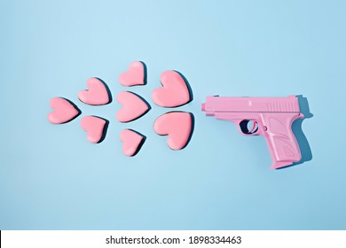 Love Layout Made With Pink Gun Firing A Pink Heart Shaped Cookies On A Pink Background. Creative Broken Heart, Food, Valentines Or Romantic Concept. Flat Lay, Top View.