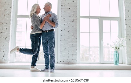 Love Lives Forever! Senior Couple At Home. Handsome Old Man And Attractive Old Woman Are Hugging And Enjoying Spending Time Together.