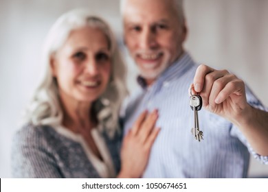 Love Lives Forever! Senior Couple At Home. Handsome Old Man And Attractive Old Woman Are Spending Time Together While Standing With Keys In Hands. Moving Day