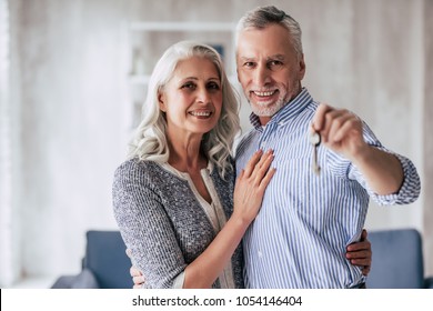 Love Lives Forever! Senior Couple At Home. Handsome Old Man And Attractive Old Woman Are Spending Time Together While Standing With Keys In Hands. Moving Day