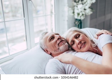 Love lives forever! Senior couple at home. Handsome old man and attractive old woman are enjoying spending time together while lying in bed. - Powered by Shutterstock