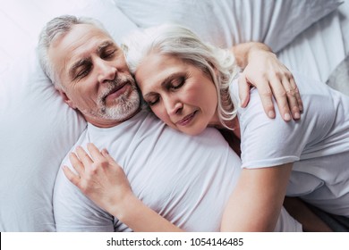 Love lives forever! Senior couple at home. Handsome old man and attractive old woman are enjoying spending time together while lying in bed.