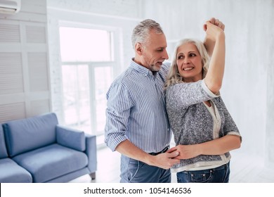 Love lives forever! Senior couple at home. Handsome old man and attractive old woman are enjoying spending time together while dancing.