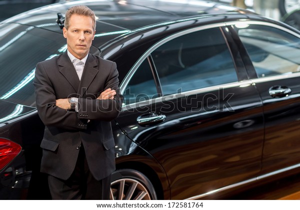 I love luxury\
cars. Top view of confident grey hair man in formalwear leaning at\
the car and looking at camera