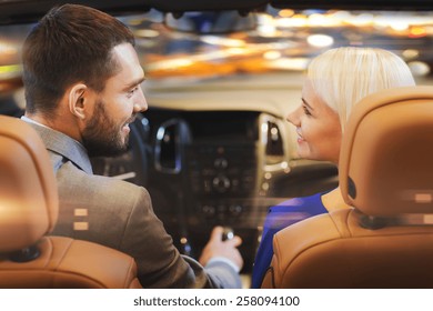 Love, Luxury, Nightlife, Automobile  And People Concept - Happy Couple Driving In Cabriolet Car Over Night City Lights Background 