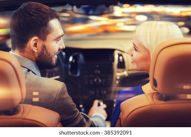 Love, Luxury, Nightlife, Automobile  And People Concept - Happy Couple Driving In Cabriolet Car Over Night City Lights Background 