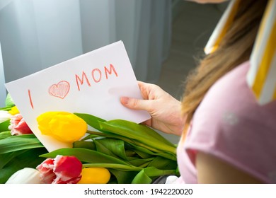 I love mom card drawing by child for Mother`s Day with yellow tulip flowers in hands of woman. Happy Birthday or Mother`s Day greetings and congratulations to mommy.