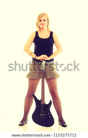 Love to music. Young pretty girl with black electric guitar. Blonde woman with passion to playing. Female musician holds instrument.